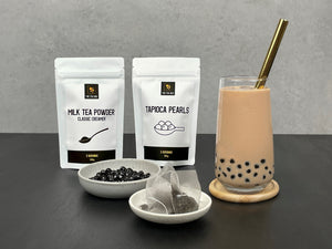 Chilled Pearl Milk Bubble tea with brown boba, gold straw. Displayed with milk tea powder, tapioca pearls and tea bags