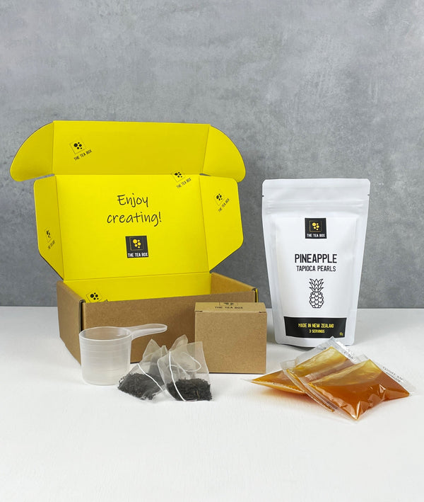 Contents of 3 pack Mango Bubble Tea Kit. Pineapple pearls in pouch, sachets of fruit mix, tea bags, scoop and cardboard gift box