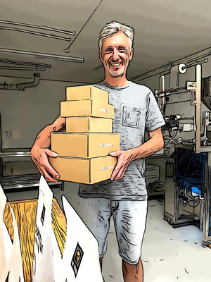 Ron in the warehouse carrying courier boxes of assorted sizes. Pouches of pearls sit on the table ready for packing