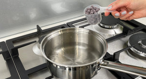 Uncooked Blueberry tapioca fruit pearls in a plastic scoop about to be added to a small pot of boiling water
