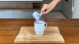 Light purple taro powder in a plastic scoop being poured into a white mug