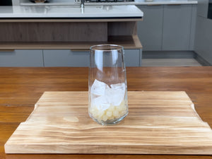 Glass holding cooked red grapefruit tapioca fruit pearls with one quarter glass of ice sitting on top of the pearls