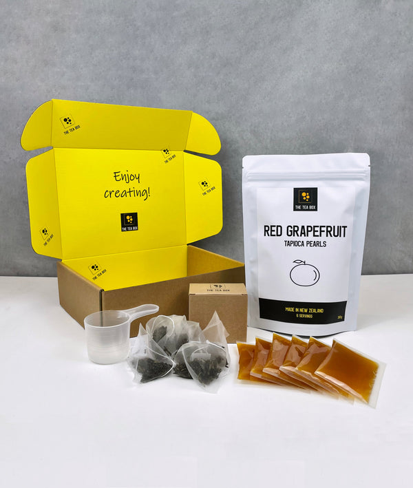 Contents of 6 pack Lychee and Passionfruit Bubble Tea Kit. Red Grapefruit pearls in pouch, sachets of fruit mix, tea bags, scoop and cardboard gift box