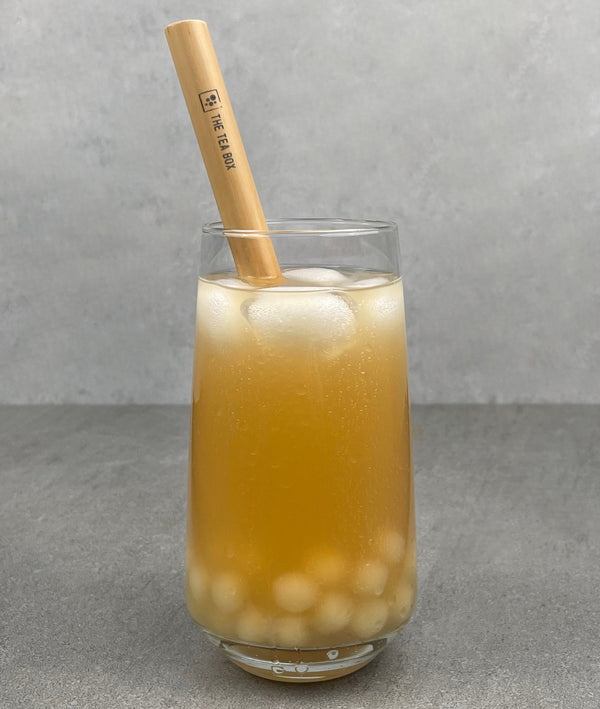 A glass of Lychee Bubble Tea with Pineapple tapioca fruit pearls, ice and a reusable bamboo bubble tea straw