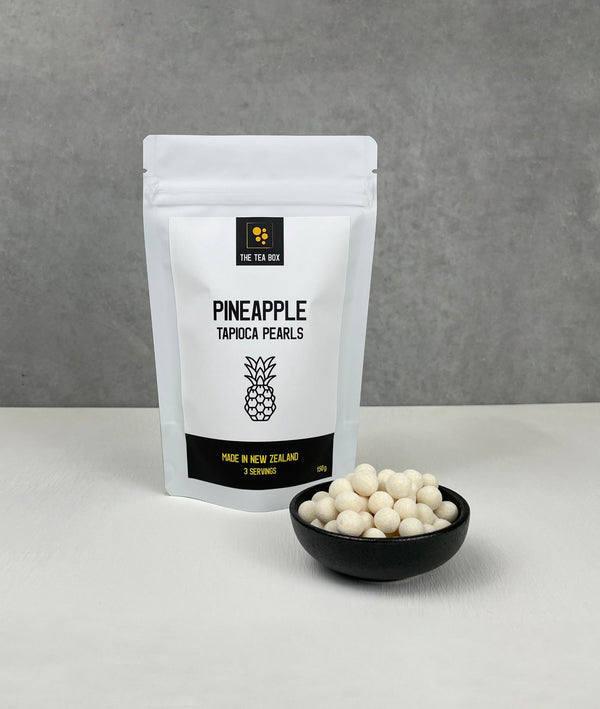 Resealable pouch holding 3 servings of Pineapple tapioca fruit pearls. Displayed with uncooked Pineapple pearls in a small ceramic dish