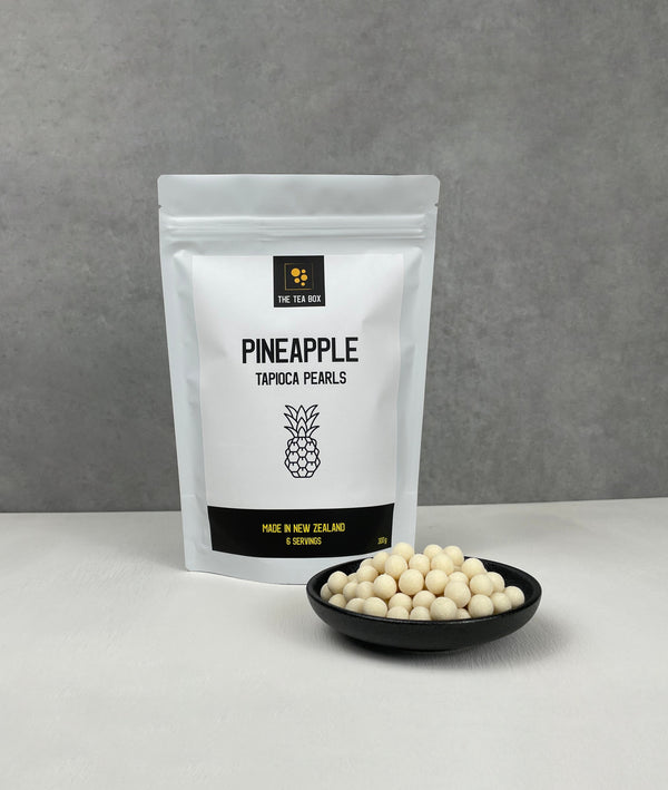 Resealable pouch holding 6 servings of Pineapple tapioca fruit pearls. Displayed with uncooked Pineapple pearls in a small ceramic dish