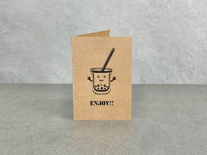Brown kraft card, titled “Enjoy!!”. A cartoon bubble tea character smiling with arms waving. 70 x 100 mm when folded
