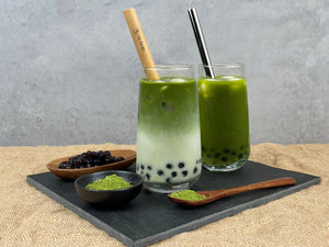 Matcha Latte and Matcha Yuzu Bubble Teas with Blueberry pearls, bamboo and silver straws. Bright green matcha powder