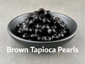 Cooked, dark brown coloured Brown tapioca pearls in a round black ceramic dish