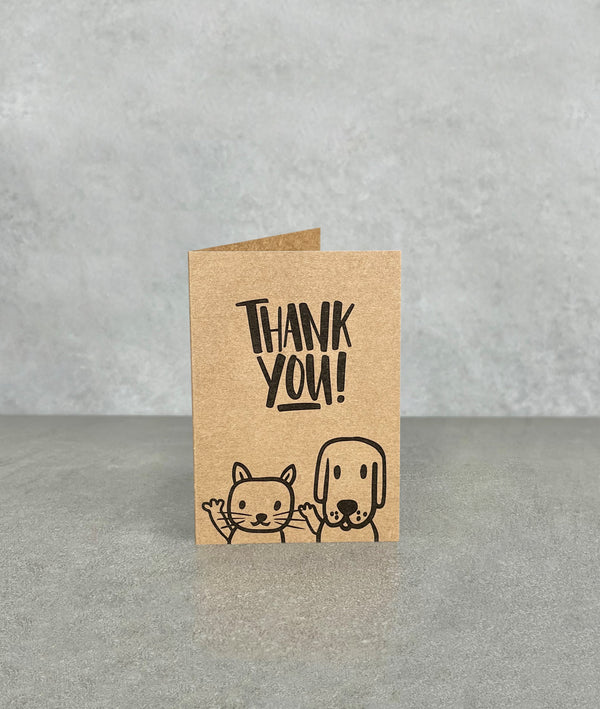 Thank You card made of brown kraft card. Shows a cartoon cat and dog, waving and smiling, with a rabbit on the back. Card measures 70 x 100 mm when folded