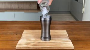 Half a glass of ice cubes being added to an antique grey stainless steel cocktail shaker