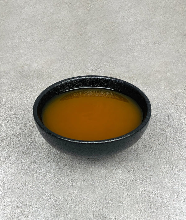 Small black ceramic dish filled with orange mango fruit mix