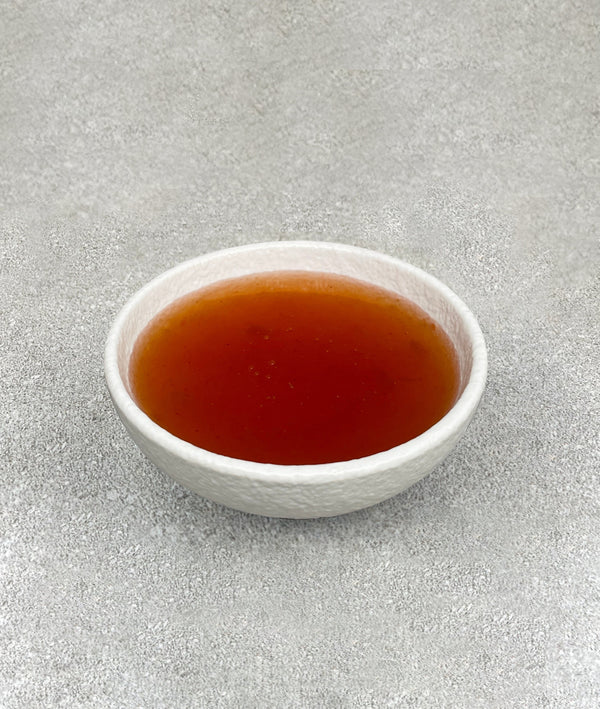 Small white ceramic dish filled with orange / red peach fruit mix