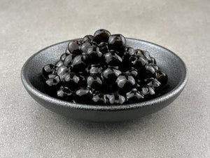 Cooked brown tapioca pearls in a round black ceramic dish