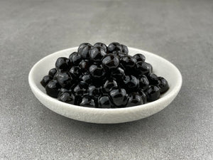 Small white ceramic dish filled with cooked shiny black tapioca pearls