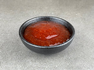 Bright red, thick Red Grapefruit fruit mix in a round black ceramic dish