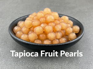 Cooked, pink, Red Grapefruit tapioca fruit pearls in a round black ceramic dish