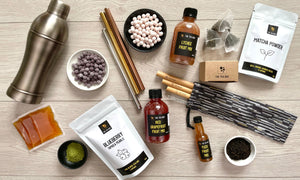 A selection of our ingredients and bubble tea accessories. Including tapioca fruit pearls, sachets and bottles of fruit mixes, matcha powder, tea leaves, an antique grey cocktail shaker, stainless steel straws and bamboo straws