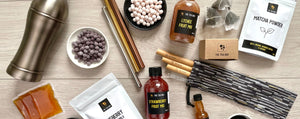 A selection of our ingredients and bubble tea accessories. Including tapioca fruit pearls, sachets and bottles of fruit mixes, matcha powder, tea leaves, an antique grey cocktail shaker, stainless steel straws and bamboo straws