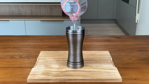One quarter of a cup of cold water being poured into an antique grey stainless steel cocktail shaker