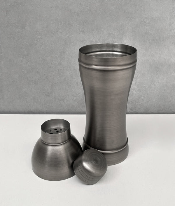 Unassembled dark antique grey 3-piece shaker. Showing the cup, strainer and cap
