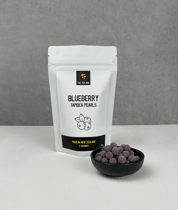 Resealable pouch holding 3 servings of Blueberry tapioca fruit pearls. Displayed with uncooked Blueberry pearls in a small ceramic dish