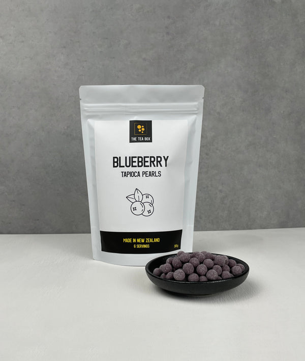 Resealable pouch holding 6 servings of Blueberry tapioca fruit pearls. Displayed with uncooked Blueberry pearls in a small ceramic dish