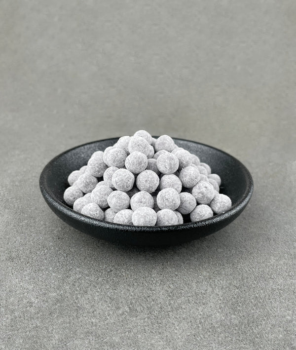 Uncooked Blueberry tapioca fruit pearls in a small black ceramic dish
