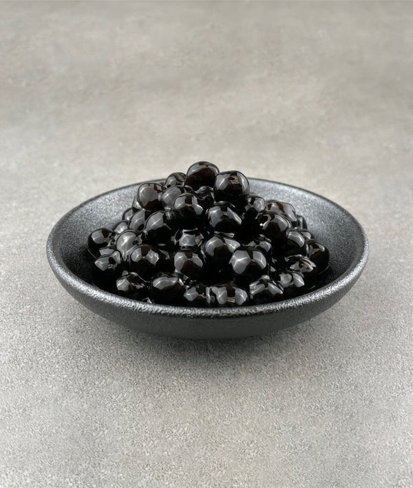 Cooked brown tapioca pearls in a black ceramic dish