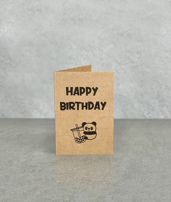 Happy Birthday card made of brown kraft card. Shows a cartoon panda clinging to a huge cup of bubble tea. Card measures 70 x 100 mm when folded
