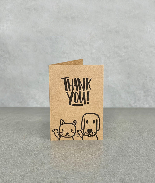Thank You card made of brown kraft card. Shows a cartoon cat and dog, waving and smiling. Card measures 70 x 100 mm when folded