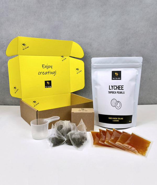 Contents of a 6 pack Passionfruit Bubble Tea Kit. Lychee pearls in a pouch, sachets of Passionfruit fruit mix, tea bags, scoop and cardboard gift box 