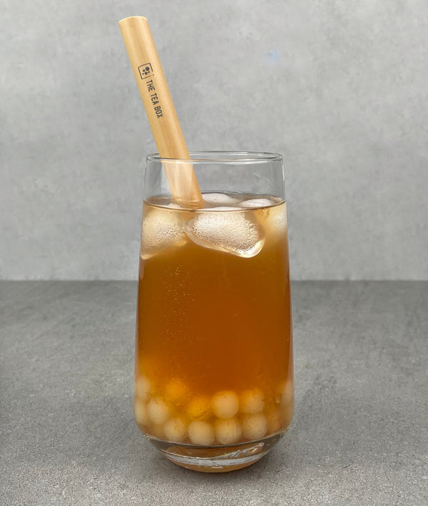 A glass of Red Grapefruit Bubble Tea with Yuzu pearls, ice and a reusable bamboo bubble tea straw