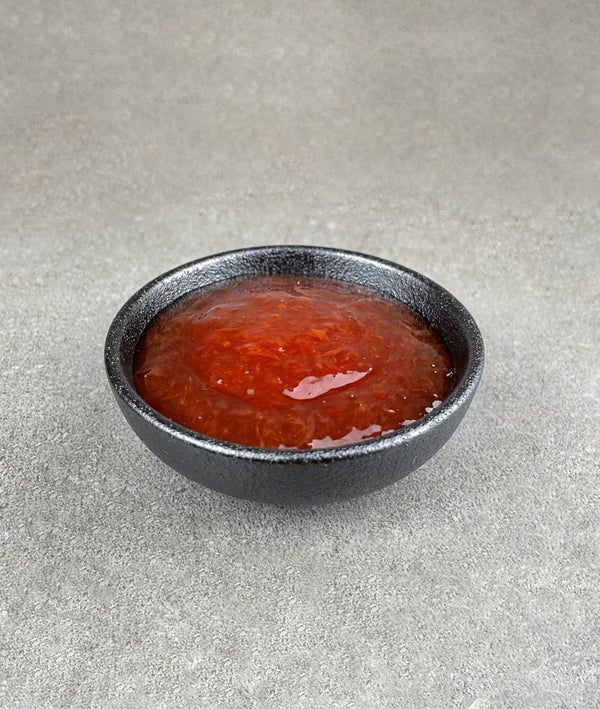 Small black ceramic dish filled with bright red, Red Grapefruit fruit mix