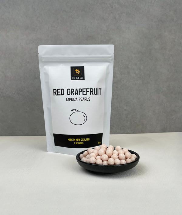 Resealable pouch holding 6 servings of Red Grapefruit tapioca fruit pearls. Displayed with uncooked Red Grapefruit pearls in a small ceramic dish