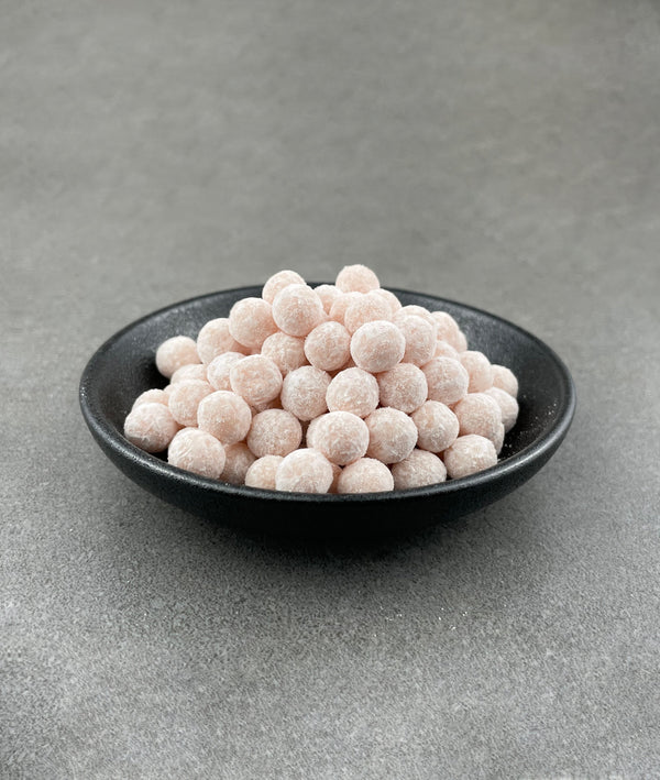 Uncooked Red Grapefruit tapioca fruit pearls in a small black ceramic dish