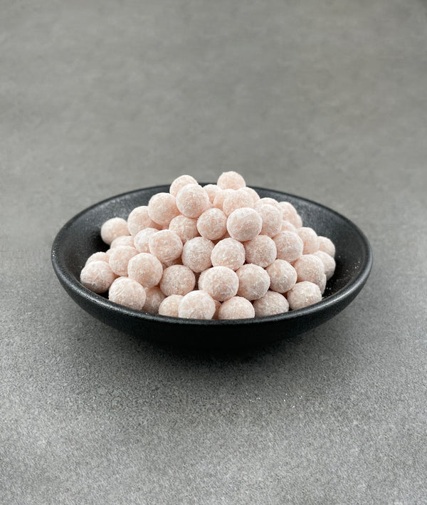 Uncooked Red Grapefruit tapioca fruit pearls in a small black ceramic dish