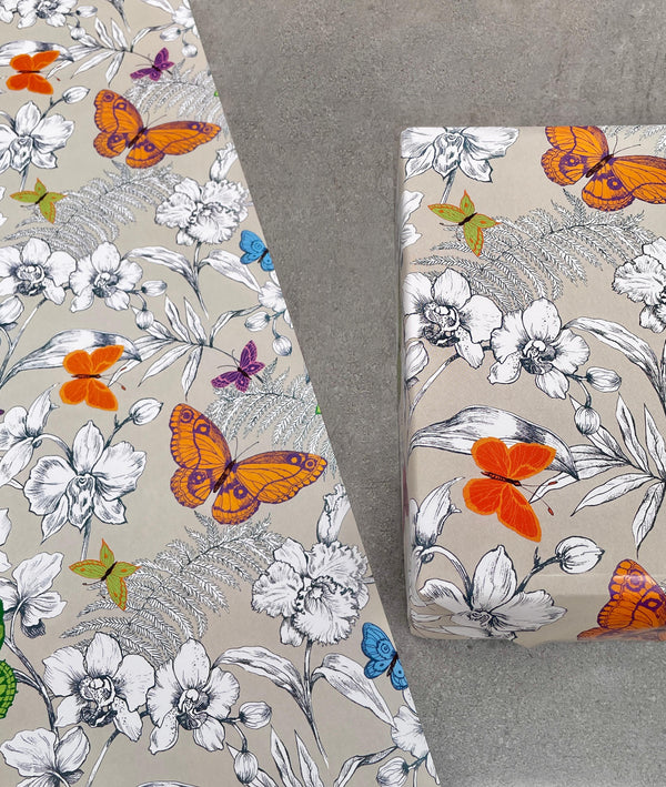 Butterflies gift wrapping paper. Brightly coloured (orange, blue, green) glossy butterflies, black and white flowers and fern foliage on grey background