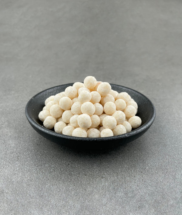 Uncooked Yuzu tapioca fruit pearls in a small black ceramic dish