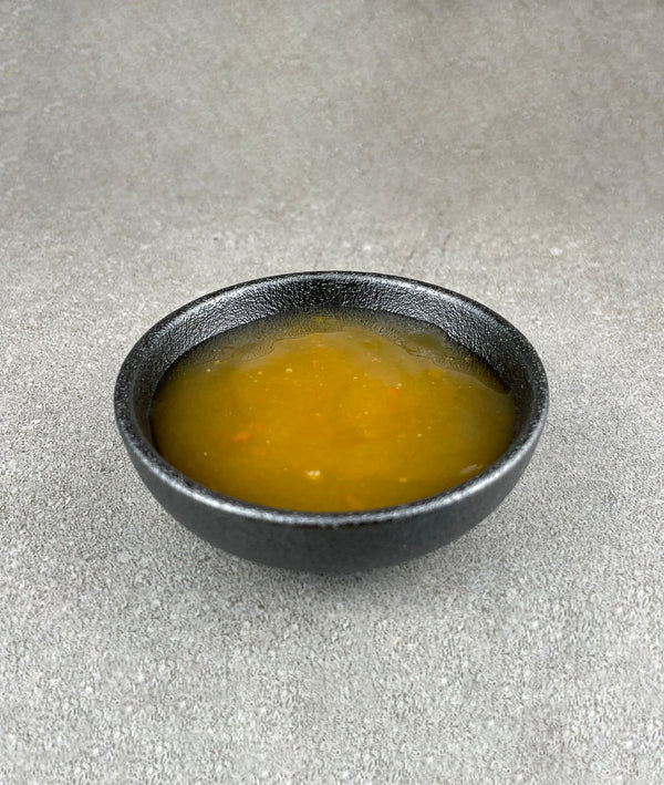 Small black ceramic dish filled with yellow Yuzu fruit mix